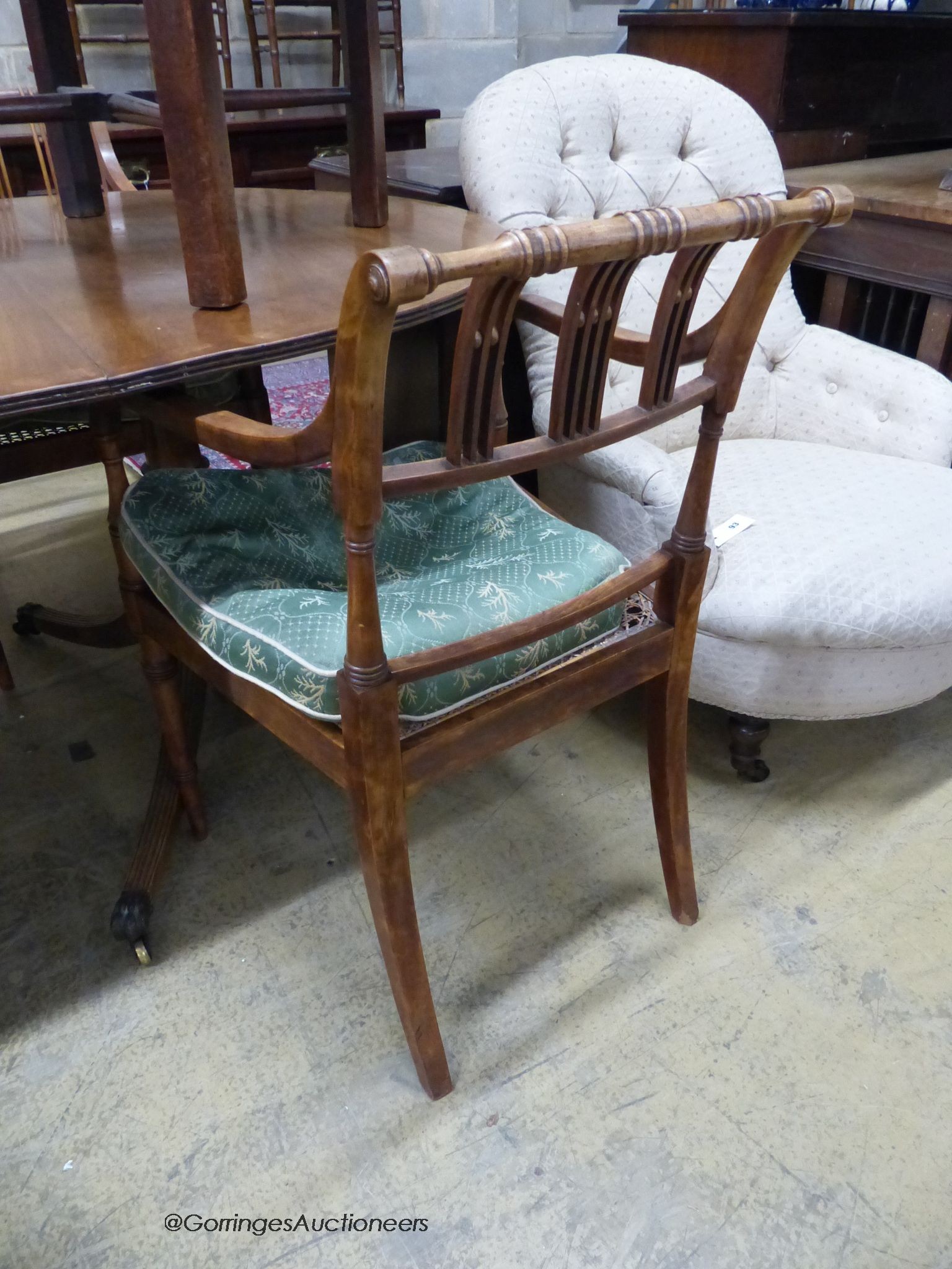 A reproduction mahogany twin pillar extending dining table and a set of six Regency fruitwood caned seated elbow chairs